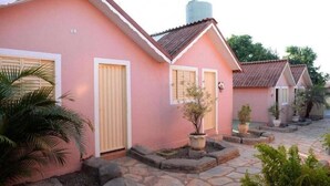 A row of pink buildings with stone pathways and potted plants. - Pousada Caldas Novas (Caldas Novas)