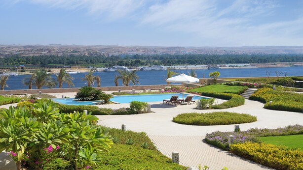 Un resort con piscina, sillas de descanso y vista al mar.
