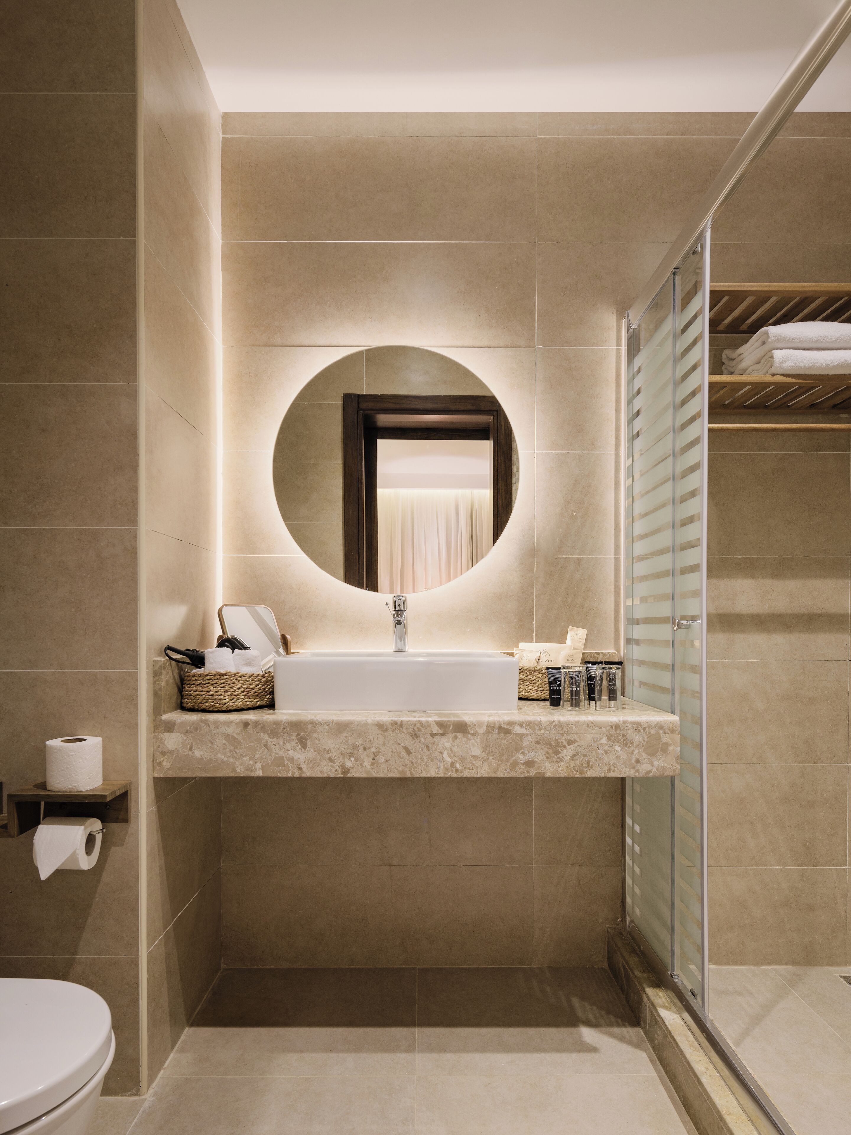 A modern bathroom with a large sink, mirror, and shower area.