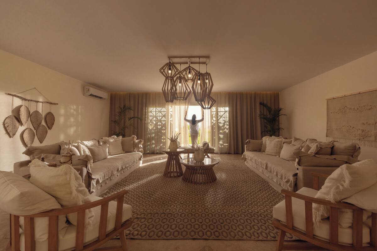 A spacious living room with a large sofa set, a coffee table, and a hanging light fixture.