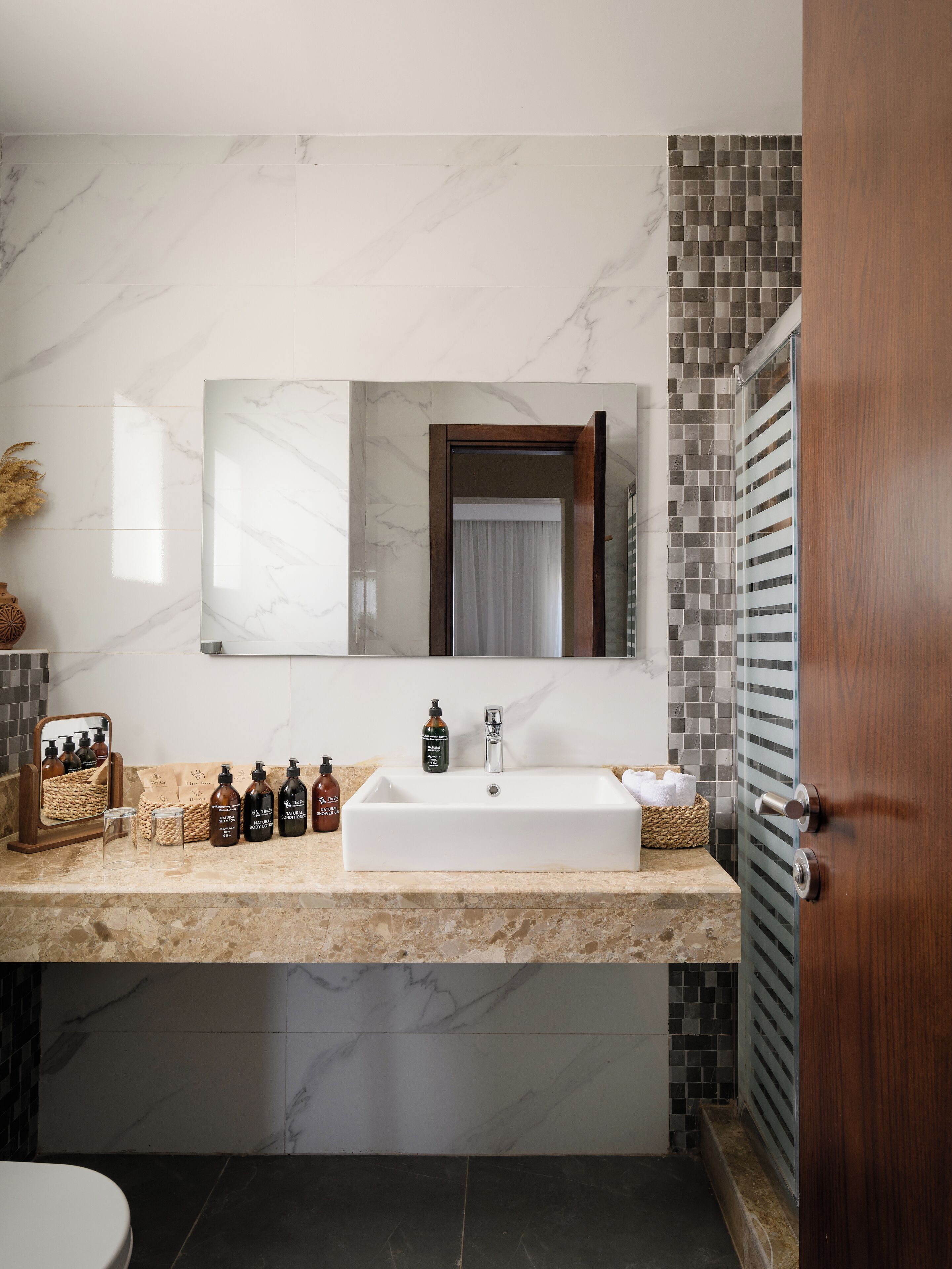 A bathroom with a large mirror, a white sink, and a tiled backsplash.