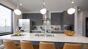 A modern kitchen with a central island, stainless steel appliances, and pendant lighting. - Cowboy Condo- Odyssey - Walk to Bars & Restaurants (Nashville)