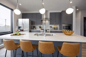 A modern kitchen with a central island, stainless steel appliances, and pendant lighting.