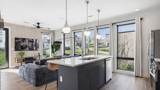 A modern kitchen with a central island, large windows, and a ceiling fan. - Cowboy Condo- Odyssey - Walk to Bars & Restaurants (Nashville)