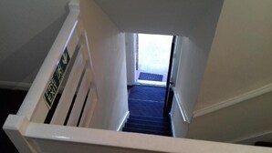 A stairwell with a white handrail and a sign indicating an exit. - Haven House Hotel (Southend-on-Sea)