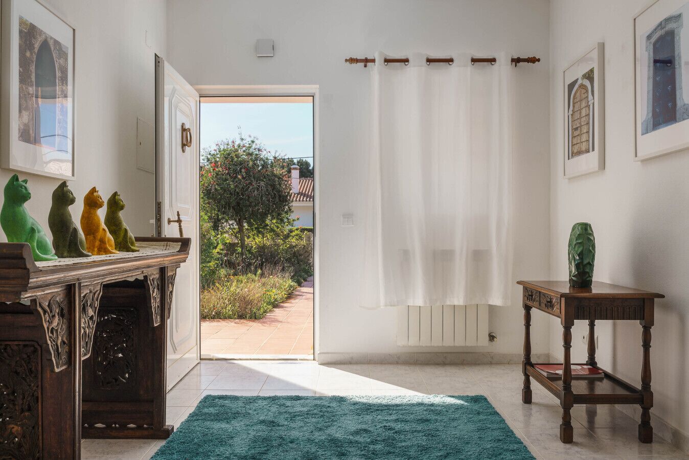 Un couloir avec un banc en bois, un tapis vert et une porte donnant sur l’extérieur.