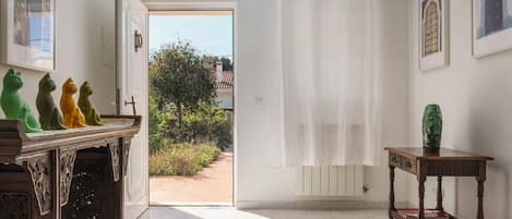Un couloir avec un banc en bois, un tapis vert et une porte donnant sur l’extérieur.