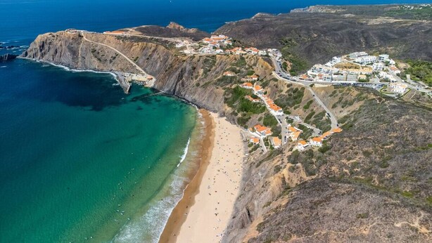 An aerial view of a coastal town with a beach, buildings, and a road. - Clifftop Nest Arrifana by Lisbeyond (Aljezur)