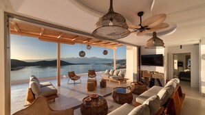 A spacious living area with a large window overlooking a scenic view, furnished with sofas, chairs, and a ceiling fan.