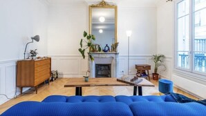 A room with a fireplace, a mirror, a wooden dresser, and a blue sofa.