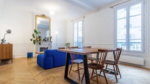 A spacious room with a wooden dining table, blue sofa, and a large mirror.