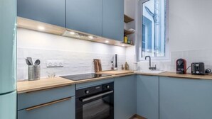 A modern kitchen with light blue cabinets, a wooden countertop, a built-in oven, and a window providing natural light.