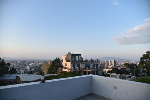 A modern building with a glass facade, surrounded by urban landscape and distant mountains.