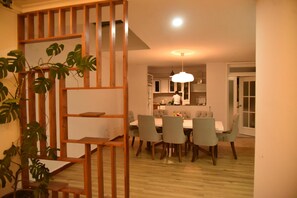 A dining area with a wooden partition, a dining table with chairs, and a hanging light fixture.