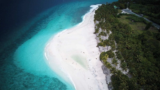 An aerial view of a beach with white sand, clear turquoise waters, and dense palm trees. - Silver County Fuvahmulah (Fuvahmulah)