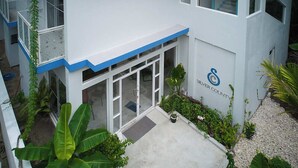 A building with a white exterior and blue trim, featuring a large glass door entrance and a logo with a blue 'C' and text. - Silver County Fuvahmulah (Fuvahmulah)