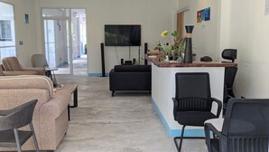 A modern reception area with a flat-screen TV, black chairs, a reception desk, and a large window. - Silver County Fuvahmulah (Fuvahmulah)