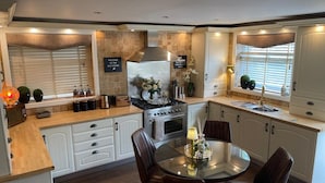A modern kitchen with white cabinetry, a central island with chairs, a stove, and a sink. - 'cosy Cottage' - 2 Bed High End Cottage in Bawtry (Doncaster)