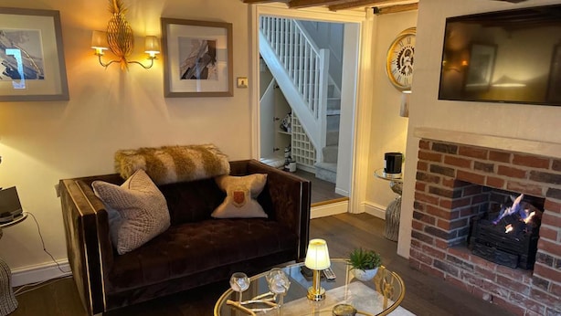 A cozy living room with a dark brown leather sofa, a glass coffee table, and a fireplace. - 'cosy Cottage' - 2 Bed High End Cottage in Bawtry (Doncaster)