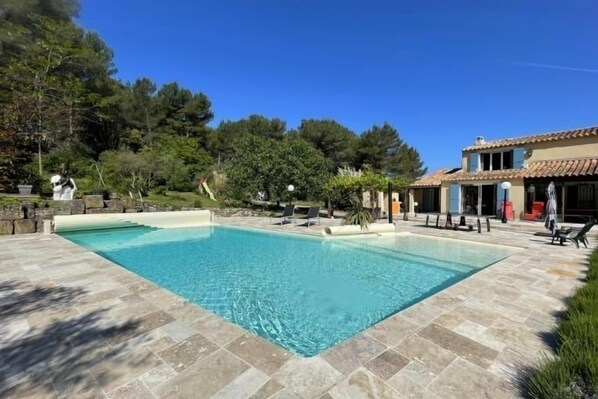 Relax by the serene pool surrounded by lush greenery and trees.