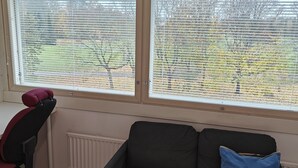 A room with a black sofa, a red office chair, and a window with blinds. - Pet-friendly 4 Bed Apt in Turku With Park Views (Turku)
