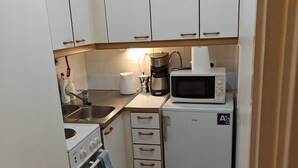A compact kitchen with white cabinets, a stove, a microwave, and a coffee maker. - Pet-friendly 4 Bed Apt in Turku With Park Views (Turku)