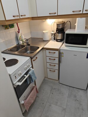 A compact kitchen with a sink, stove, oven, microwave, and a coffee maker. - Pet-friendly 4 Bed Apt in Turku With Park Views (Turku)