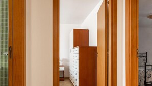 Un pasillo con una puerta de madera que da a un dormitorio con una cama y un aparador.