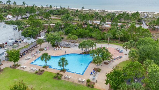 Resort com piscina, cadeiras de descanso e vista para a praia.