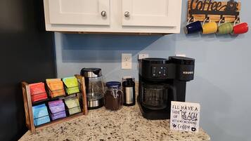 A kitchen counter with a coffee maker, mugs, and a sign that says "I'll have a side of beach with my morning coffee."
