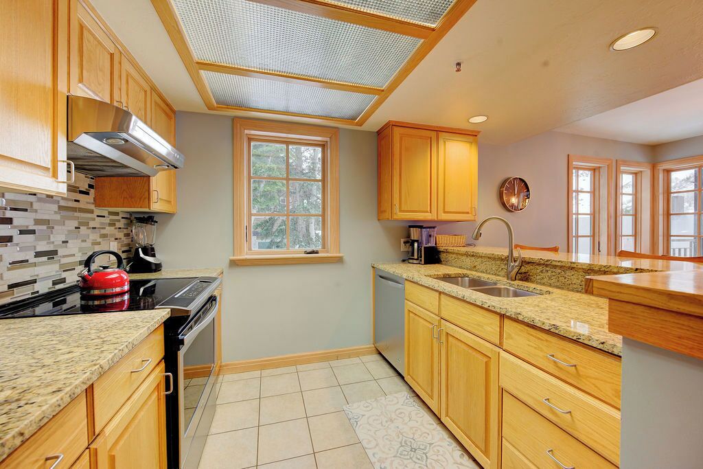 A kitchen with wooden cabinets, a granite countertop, a built-in stove, and a window.