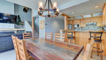 Una cocina moderna con armarios de madera, una amplia mesa de comedor y una lámpara colgante original.