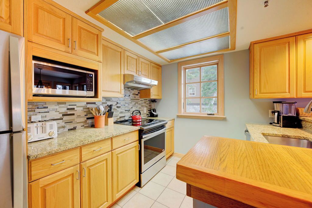 A kitchen with wooden cabinets, a microwave, a stove, and a window.