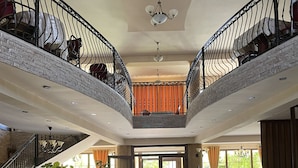 A spacious lobby with a grand piano, a staircase, and a dining area with red chairs. - ROZAFA (Bujanovac)