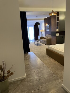 Een moderne hotelkamer met een groot bed, een bank, een klein tafeltje en een potplant.