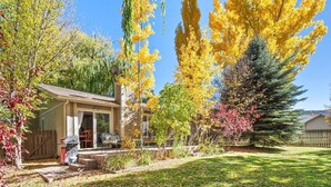 A residential property with a covered patio, a lawn, and various trees in autumn colors.