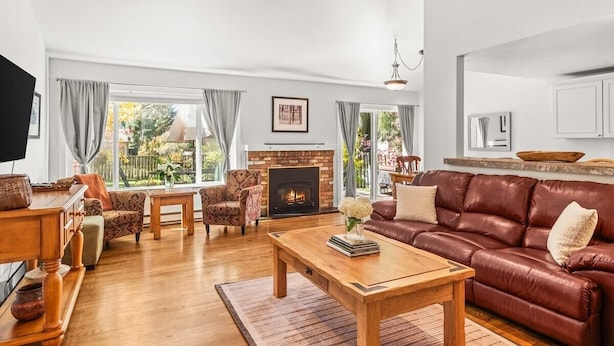 A spacious living room with a fireplace, leather sofa, wooden coffee table, and patterned armchairs.