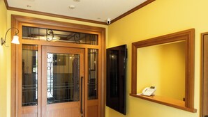 Une porte en bois avec des panneaux de verre et un téléphone posé sur une étagère.