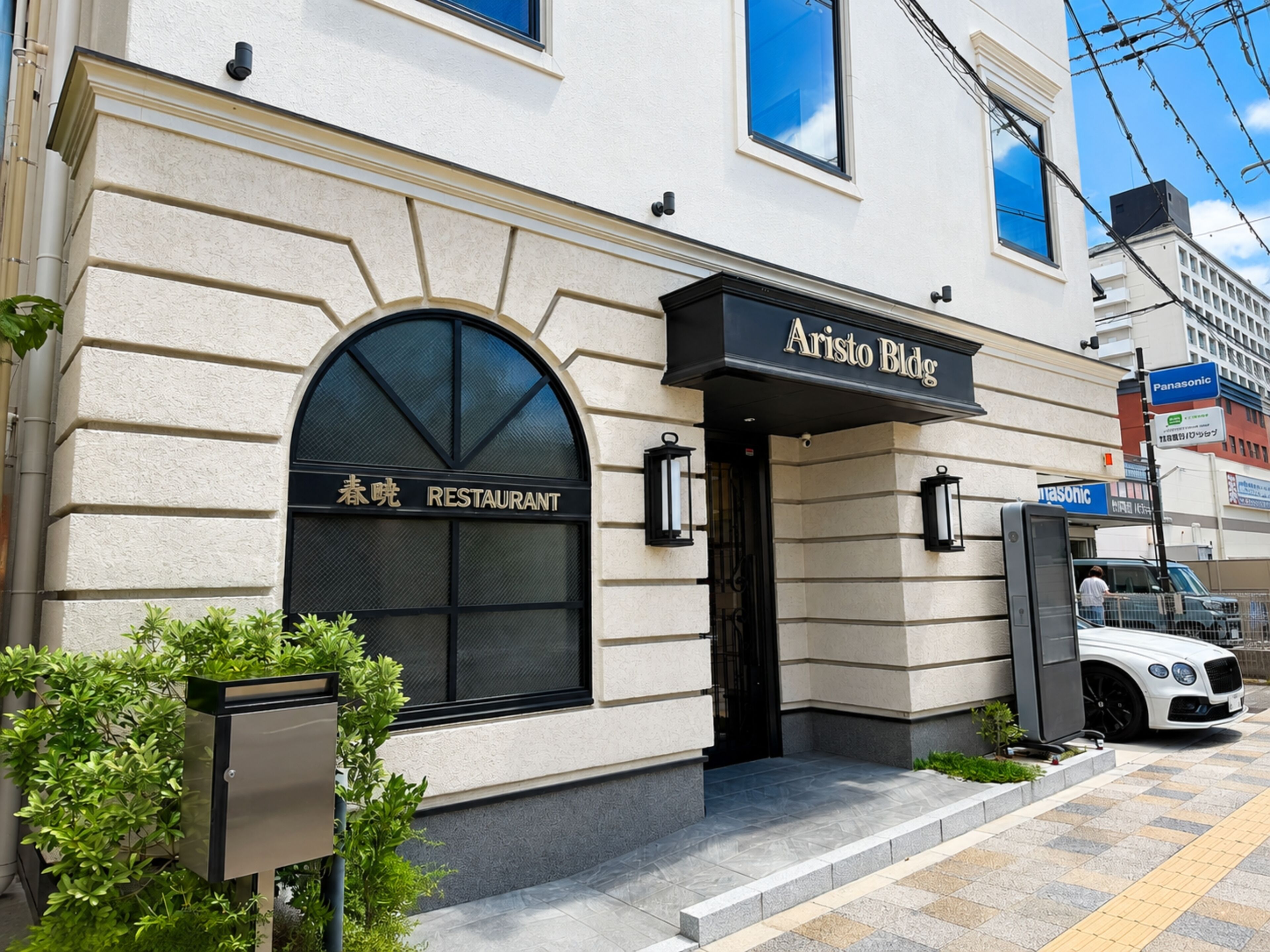 A restaurant with a black awning and a sign that reads 'Aristo Bldg.'