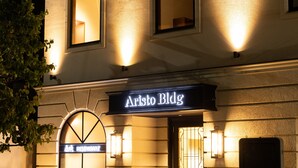 Un immeuble avec une enseigne indiquant « Aristo Bldg » et une enseigne de restaurant au-dessus de l’entrée.