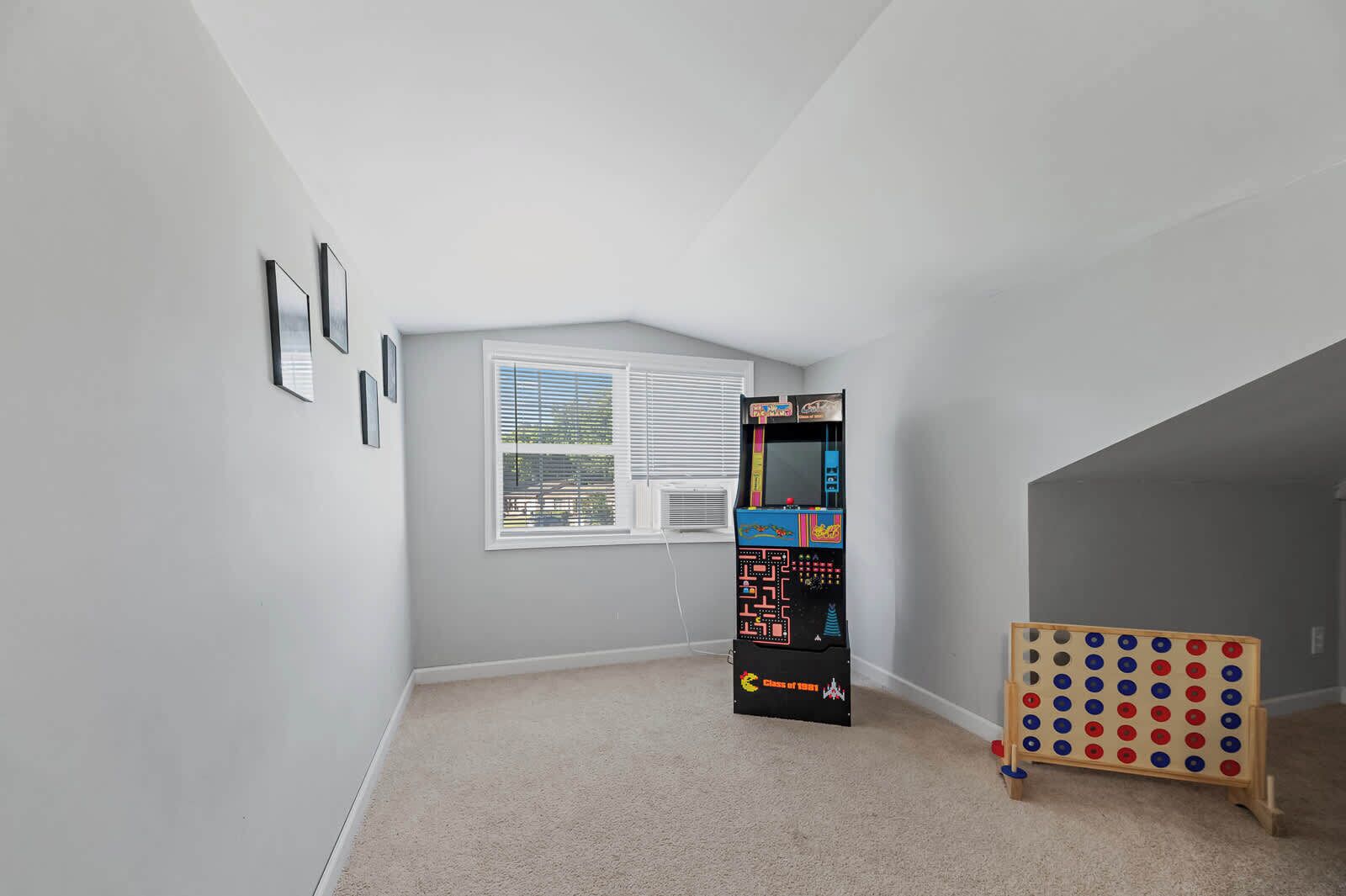 A room with a window, a game machine, and a wooden pegboard.