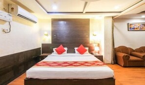 A hotel room with a bed, a nightstand, a lamp, and a couch.
