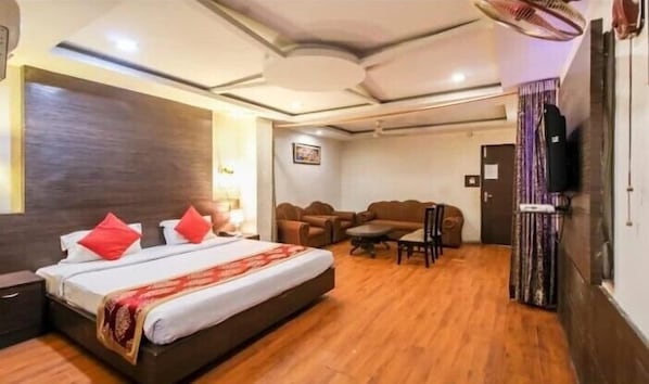 A hotel room with a bed, a sofa, a small table, and a television.