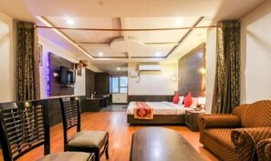 A hotel room with a bed, a desk, a chair, and a sofa.