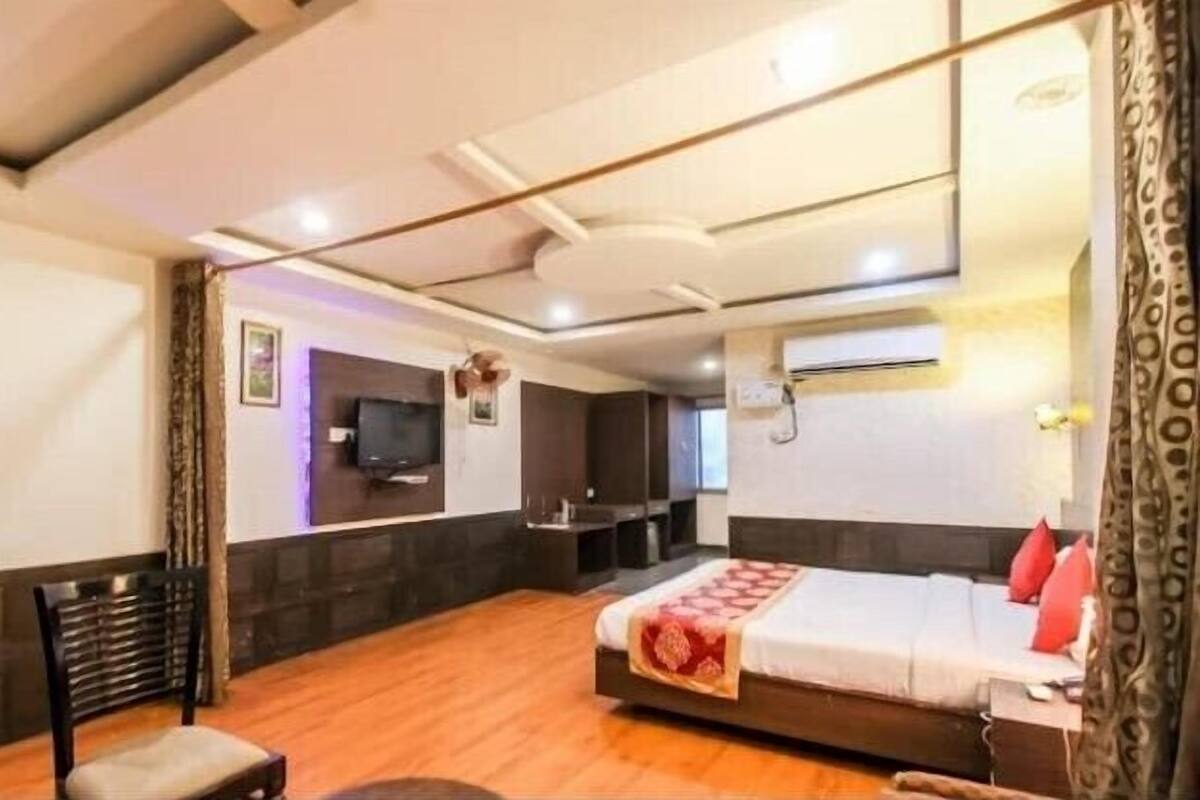 A hotel room with a bed, a TV, a desk, and a chair.