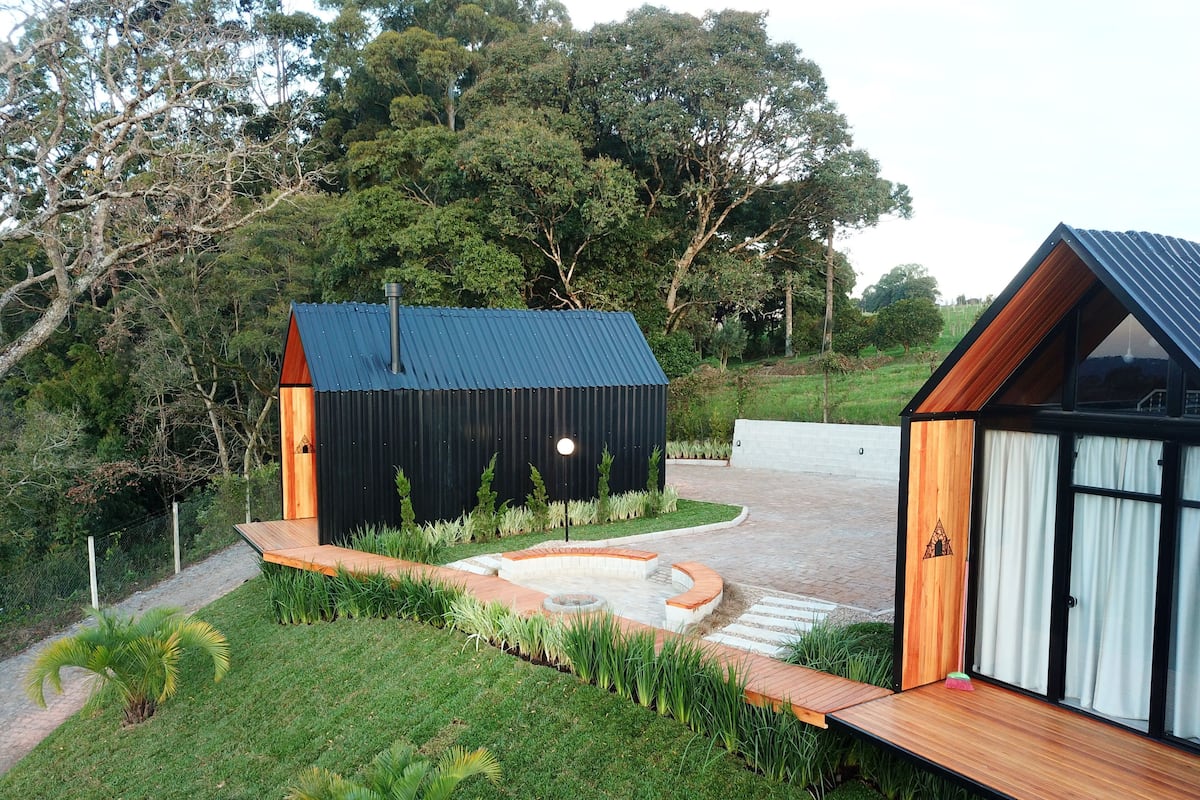 A modern house with a black exterior, wooden deck, and a small garden area with grass and plants.
