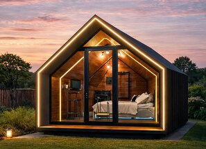 Eine moderne, A-förmige Holzhütte mit Bett, Schreibtisch und Fernseher.