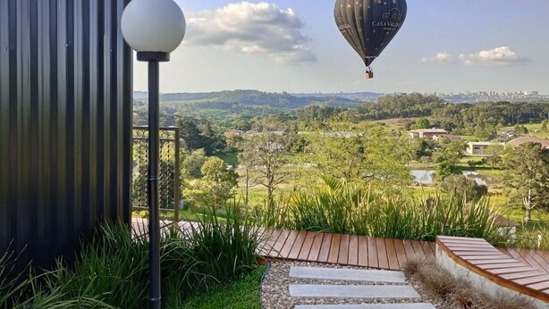 A hot air balloon with "CASA VALDO" written on it flying over a landscape with a metal building and a lamp post in the foreground. - Alta Vista Cabanas (Garibaldi)