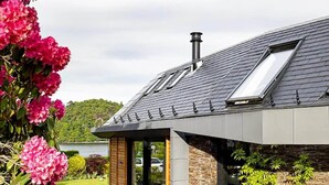 Ein modernes Haus mit Satteldach, Oberlicht und einer Steinfassade.