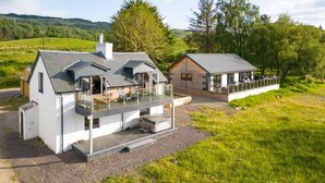 Una casa moderna con una amplia terraza, un espacio exterior cubierto y vistas del campo circundante.